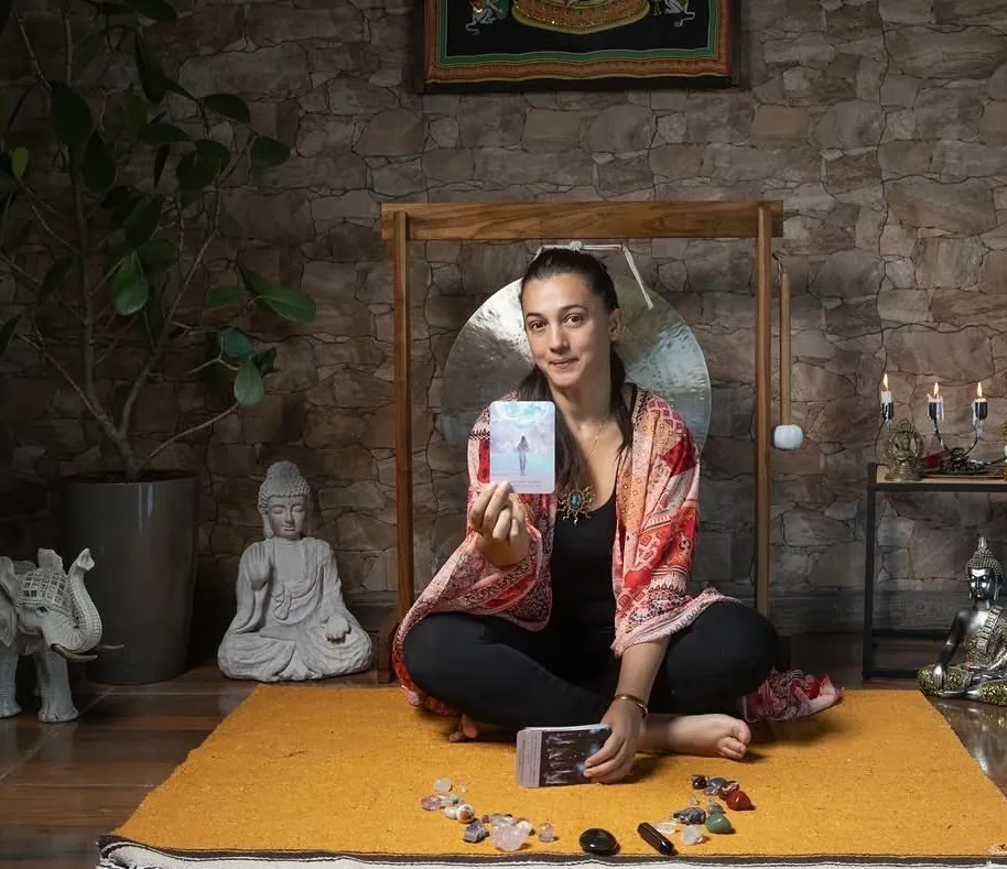 Andrea mostrando una carta durante una lectura, con cristales sobre la alfombra