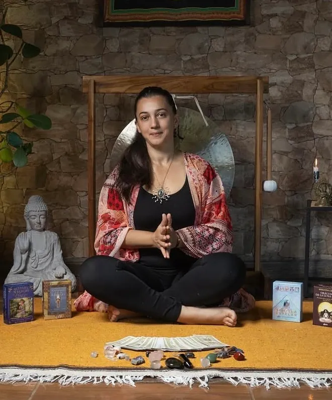 Andrea Marín sentada frente a sus cartas y cristales