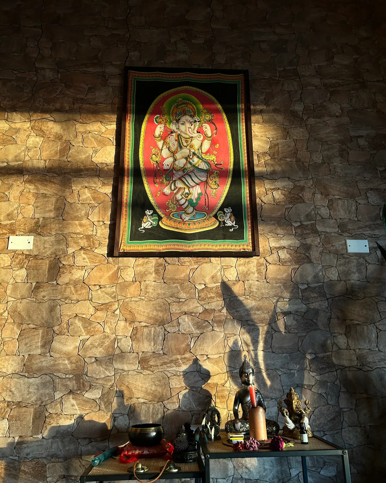 El tapiz de Ganesha sobre la pared de piedra, con el altar debajo