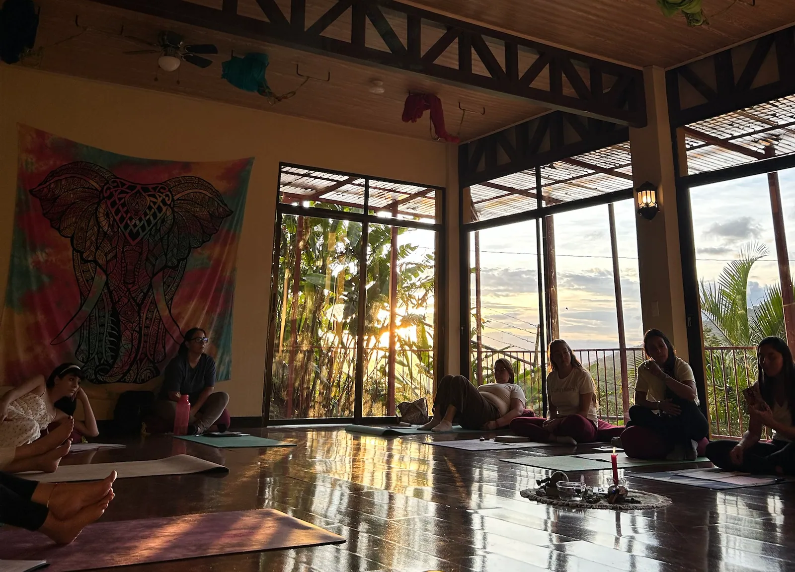 Un taller en el salón: el grupo sentado en círculo alrededor de una vela, con el sol entrando por los ventanales